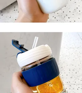 Close-up of a stylish glass coffee cup featuring a blue silicone sleeve and straw