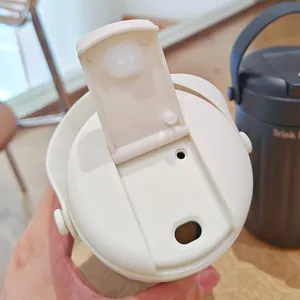 Detail view of the cream flip-top lid with dual drinking holes on an insulated mug