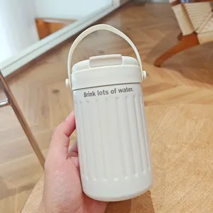 Detailed hand-held view of a cream-colored minimalist insulated water bottle with handle