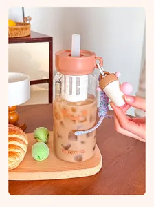Nahaufnahme einer niedlichen Glasflasche mit Smile-Gesicht, Teesieb und Trinkhalm