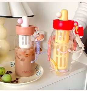 Nahaufnahme süßer Glas-Wasserflaschen mit Smiley, Teefilter und bunten Deckeln.