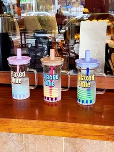 Trois gobelets en verre colorés avec poignées et pailles, texte 'Relaxed Time' sur bois.