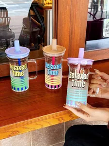 Vue rapprochée de trois tasses en verre stylées avec poignées et pailles colorées