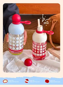 Two designer glass water bottles with straw and red ball caps on a cozy background