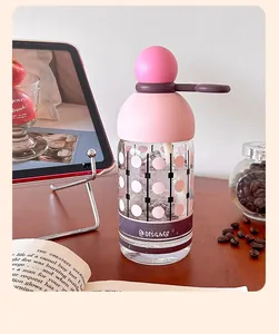 Creative high borosilicate glass water bottle with pink lid and straw on a desk.