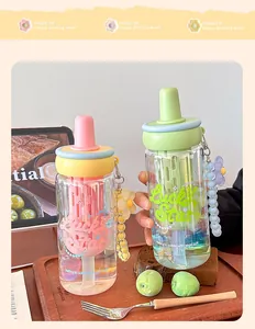 Close-up of portable glass tea bottle with filter, straw, and cute flower pendant