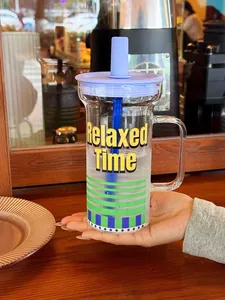 Vue détaillée d'une grande tasse en verre avec anse, couvercle violet et paille.