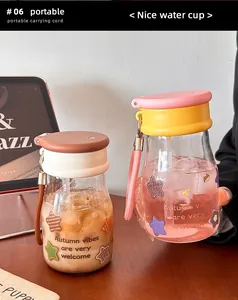 Gros plan de deux tasses à eau en verre portables et résistantes à la chaleur avec couvercles colorés