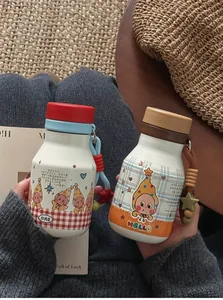 Nahaufnahme von zwei süßen tragbaren Mini-Isolierflaschen mit Sternen-Design und Tragegurt.