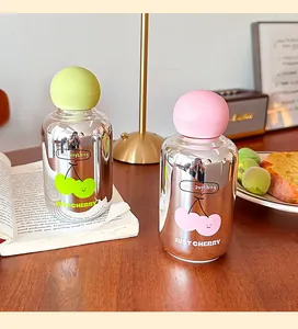 Vue détaillée de gourdes en verre miroir cerise avec bouchons rose et vert sur une table.