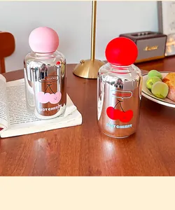 Vue détaillée de bouteilles d'eau en verre miroir avec imprimés cerises sur table