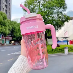 Close-up view of a pink minimalist plastic water cup with straw and handle held outdoors
