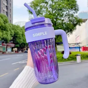 Detailed view of a stylish purple plastic straw cup with handle held outdoors.