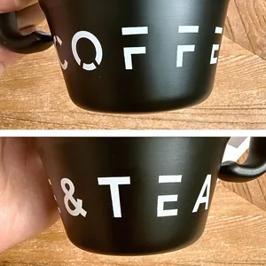 Detailansicht des weißen COFFEE und TEA Textes auf einem mattschwarzen Kaffeebecher
