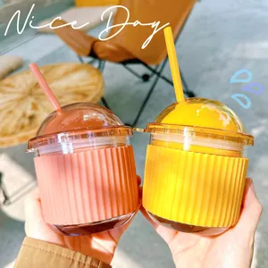 Two cute egg-shaped glass straw cups with pink and yellow silicone sleeves in a cafe setting.