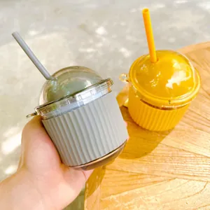 Close-up of egg-shaped glass straw cups with grey and yellow silicone sleeves