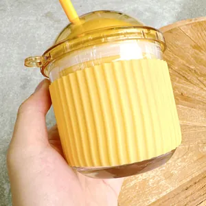 Close-up of cute yellow egg-shaped glass cup with straw and silicone sleeve