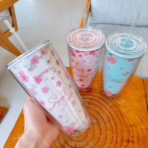 Détail de trois gobelets en plastique à double paroi avec motifs de sakura roses.