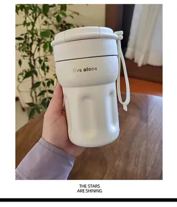 Close-up of minimalist white portable coffee cup with a convenient hand strap