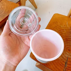 Vue rapprochée d'un gobelet rose à double paroi avec couvercle et paille clairs