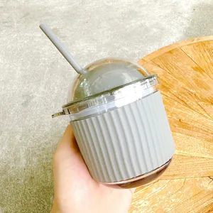 Close-up of hand holding a cute egg-shaped glass straw cup with grey silicone sleeve