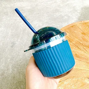 Close-up view of a minimalist blue egg-shaped glass cup with a silicone sleeve and straw