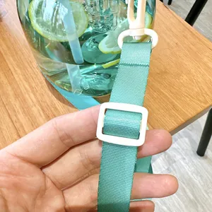 Close-up showing the adjustable turquoise strap and white plastic buckle on the water bottle.