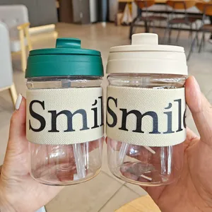 Hände halten zwei tragbare Kunststoff-Kaffeetassen mit „Smile“ Anti-Verbrühungs-Manschetten.