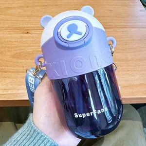 Handheld view of a cute purple bear-shaped water bottle for kids with strap