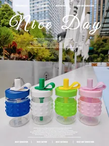 Four colorful glass water bottles with heart-patterned silicone sleeves in an outdoor setting