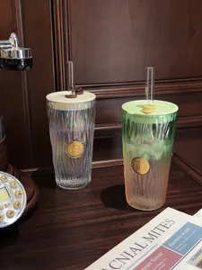 Textured gradient and iridescent glass tumblers with straws on a dark wooden desk
