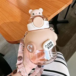 Dettaglio di una borraccia in plastica a forma di orso con cannuccia e tracolla.