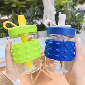 Close-up of glass straw cups with heart pattern silicone sleeves in green and blue