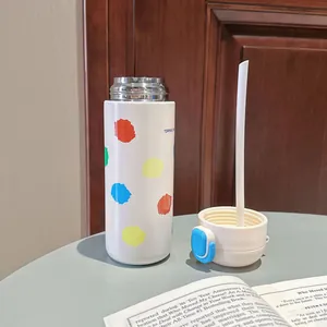 Detailansicht einer bunten Isolierflasche mit Strohhalm und blauem Verschlussknopf.