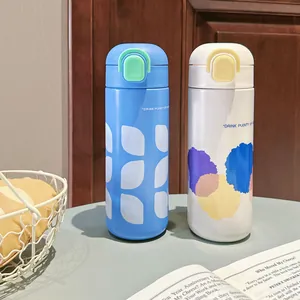 Nahaufnahme von stilvollen blau-weißen Isolierflaschen mit Strohhalm auf einem Tisch.