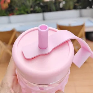Detailed macro view of pink glass straw cup featuring a protective silicone lid and strap