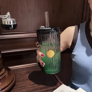 Detailed view of a gradient green glass cup featuring a straw and decorative gold seal