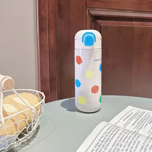 Detailansicht einer weißen Thermo-Trinkflasche mit bunten Punkten und blauem Klickdeckel