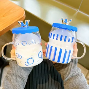 Creative Klein blue glass cups with crown lids and handles held in hands for detail view.