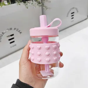 Detail of pink silicone heart-pattern sleeve on portable glass straw water bottle.