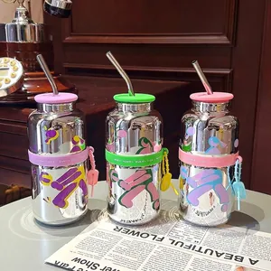 Détail de trois gobelets en verre effet miroir avec pailles et bandes en silicone