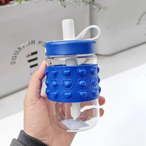 Close-up view of clear glass straw water bottle with blue heart pop-it silicone sleeve