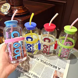 Gros plan de quatre gobelets en verre colorés avec paille et imprimé 'COOL' sur fond déco