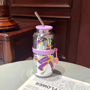 Bouteille d'eau en verre miroir avec couvercle en silicone violet et paille en métal sur table.
