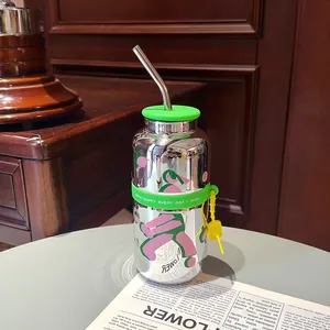 Gros plan d'un gobelet en verre miroir avec motifs floraux et bande en silicone vert