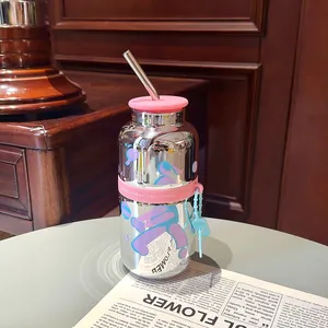 Bouteille d'eau en verre miroir avec paille métallique et détail de bande rose.