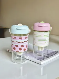 Two pastel glass water bottles with straw and protective patterned sleeves on table