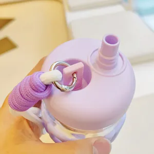 Gros plan du couvercle d'une bouteille d'eau en verre violette avec une sangle tressée.