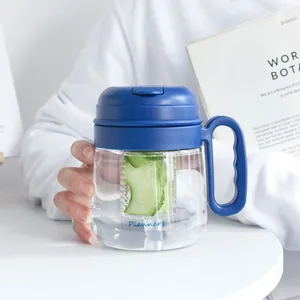 Detailansicht einer tragbaren Kunststoff-Tasse mit Teesieb und frischen Gurken