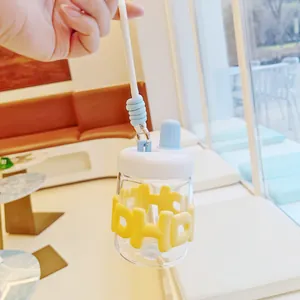Vue détaillée d'une bouteille d'eau en verre portable avec manchon en silicone jaune.
